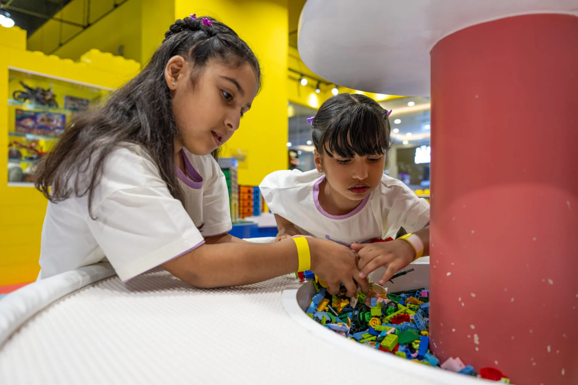 Children playing and building together with LEGO activities for kids inside a bright indoor play space